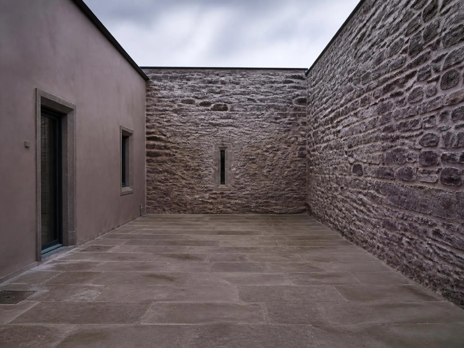 Indicative visualisation of an enclosed external courtyard paved in large limestone flags, walls on two sides and daylight from above