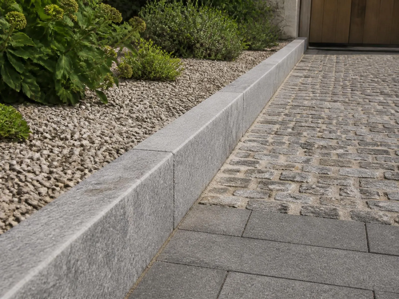 Indicative visualisation of sawn grey limestone kerb lengths forming the edge of a paved path and driveway, the edge profile clearly visible