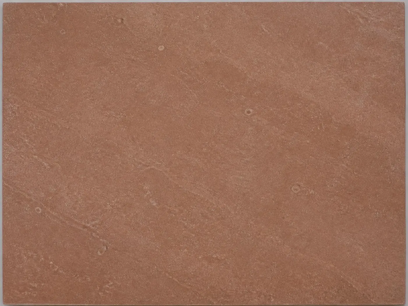 A flat honed tile of muted reddish brown Shahabad limestone, showing its even colour and fine natural surface