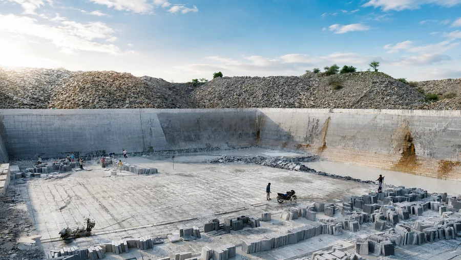 The working pit at our quarry near Miriyan village, with benched limestone walls, cut layers stacked on the floor and machinery working at the face