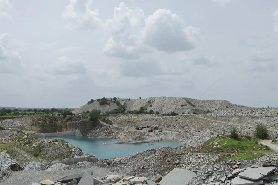 Wide view across the quarry landscape, standing water at the base of the worked limestone beds